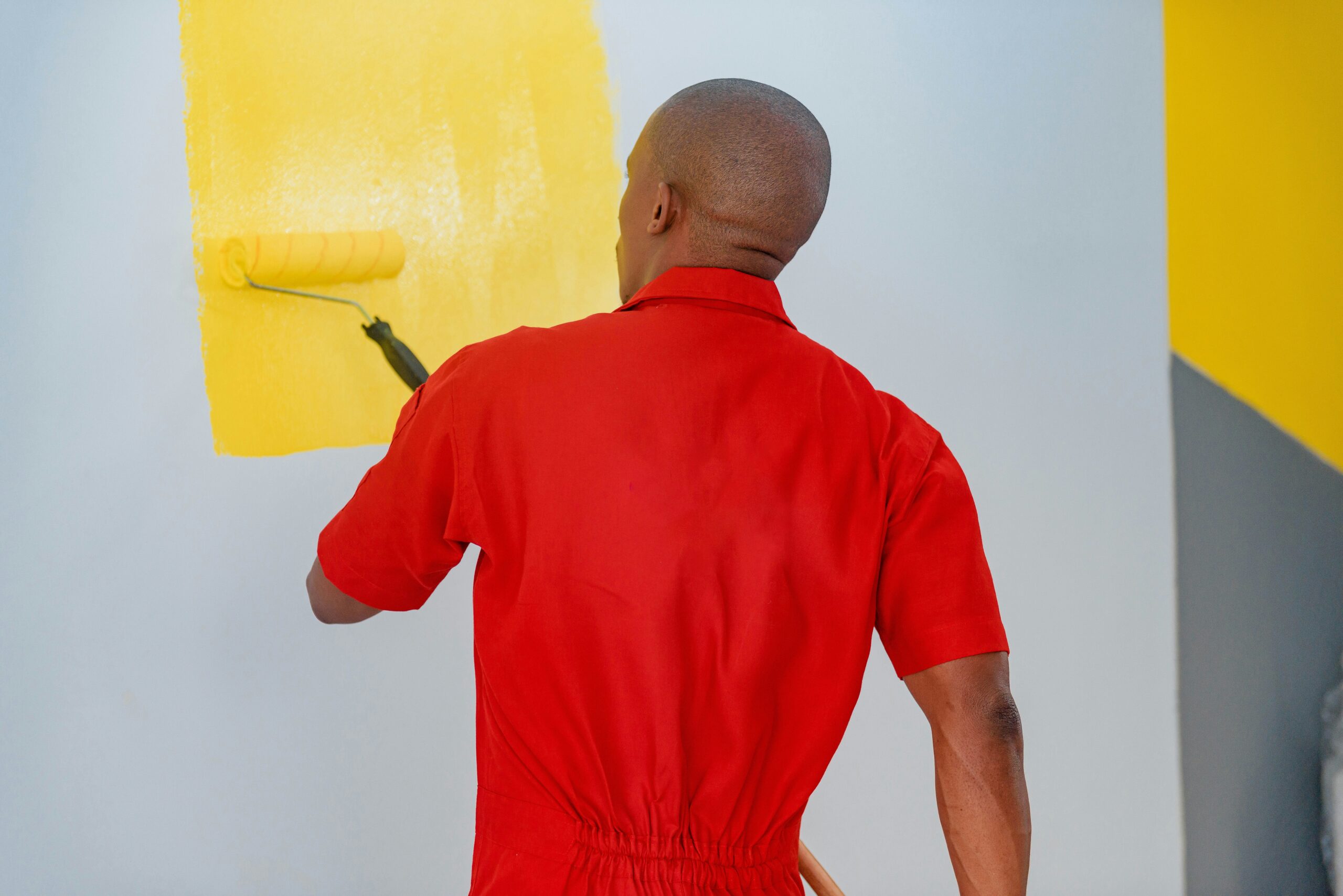 man painting wall yellow