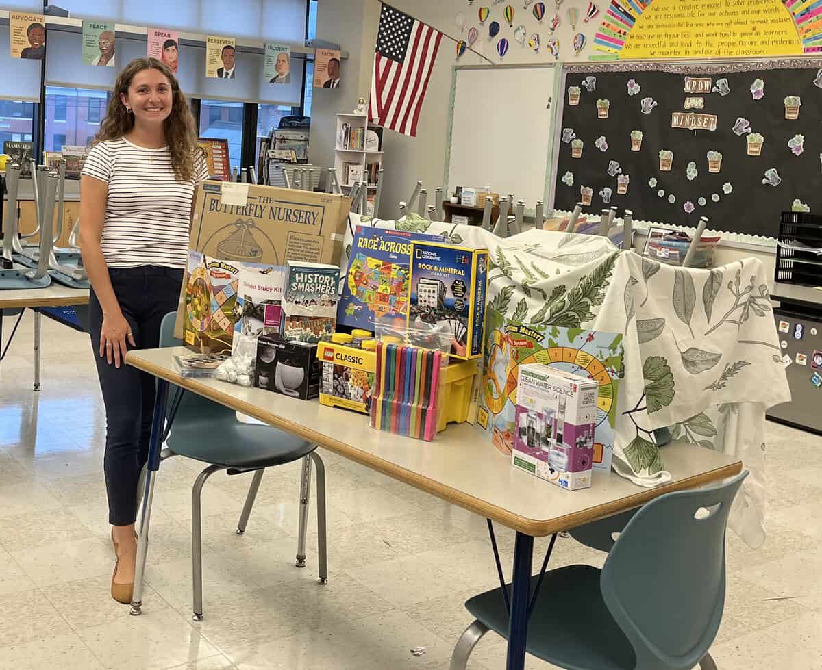 teacher in classroom showing table of books